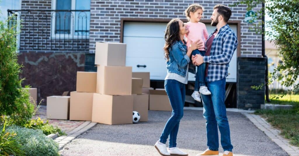 when is garage sale season - happy couple with child in front of garage sale boxes