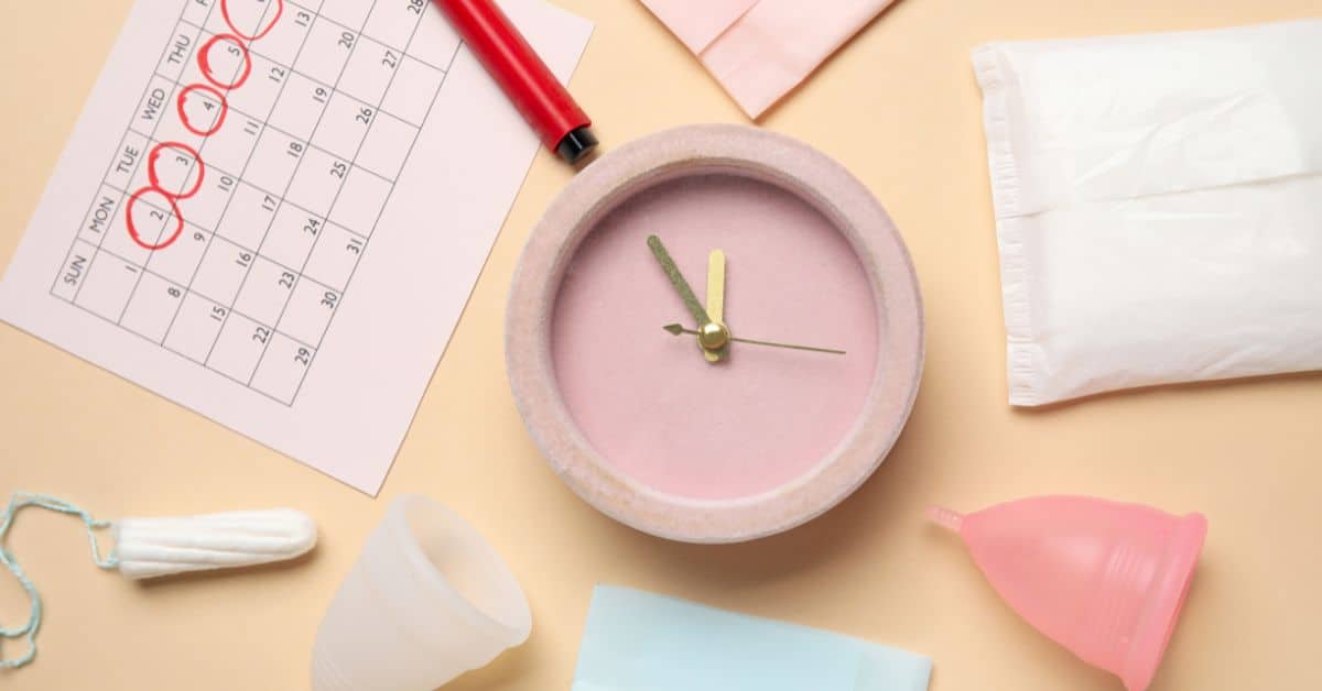 Composition with alarm clock, menstrual calendar and different feminine hygiene products on color background